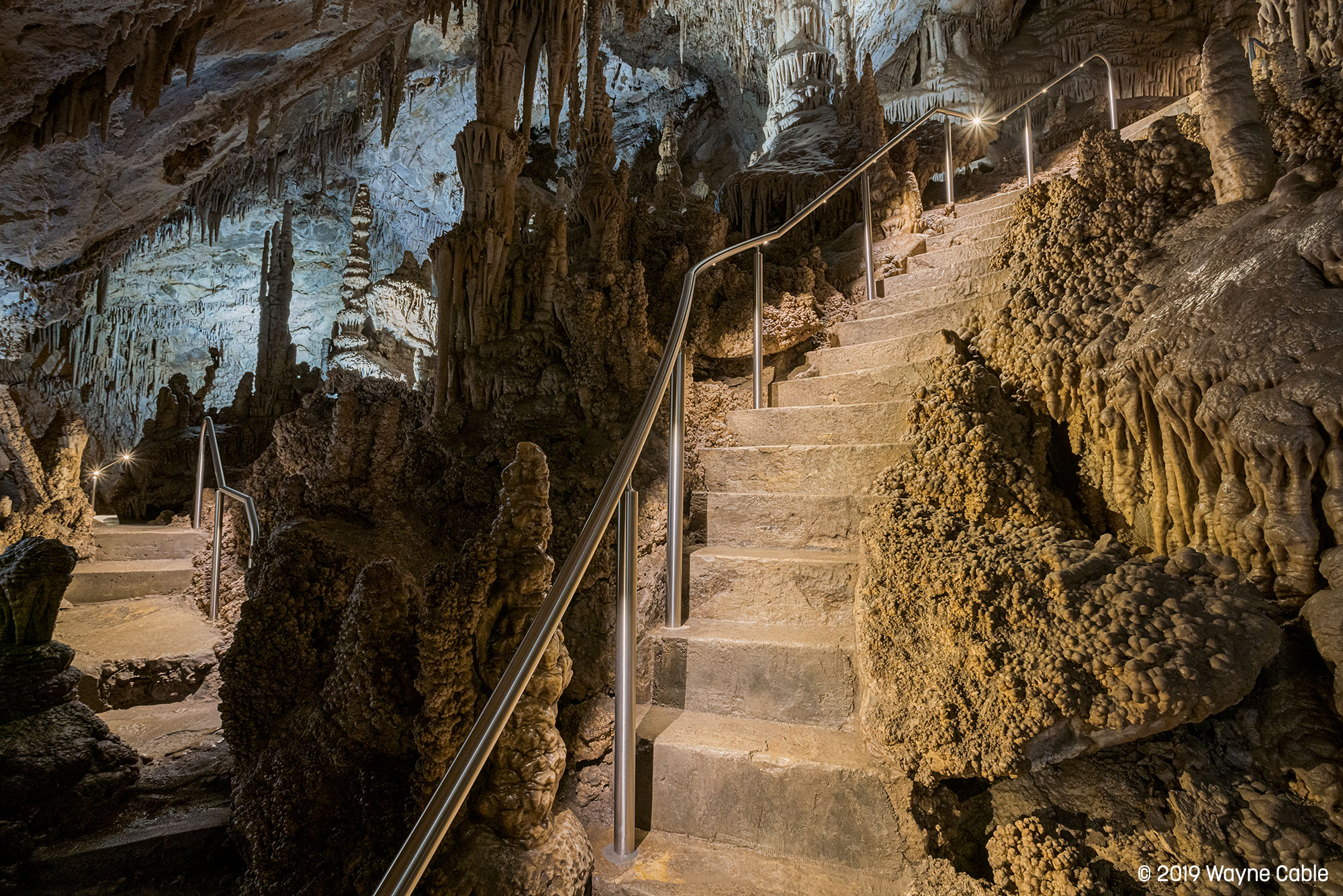 Stone staircase with Lumenpod 28 lighting in Lewis and Clark Caverns, Montana, surrounded by natural rock formations.